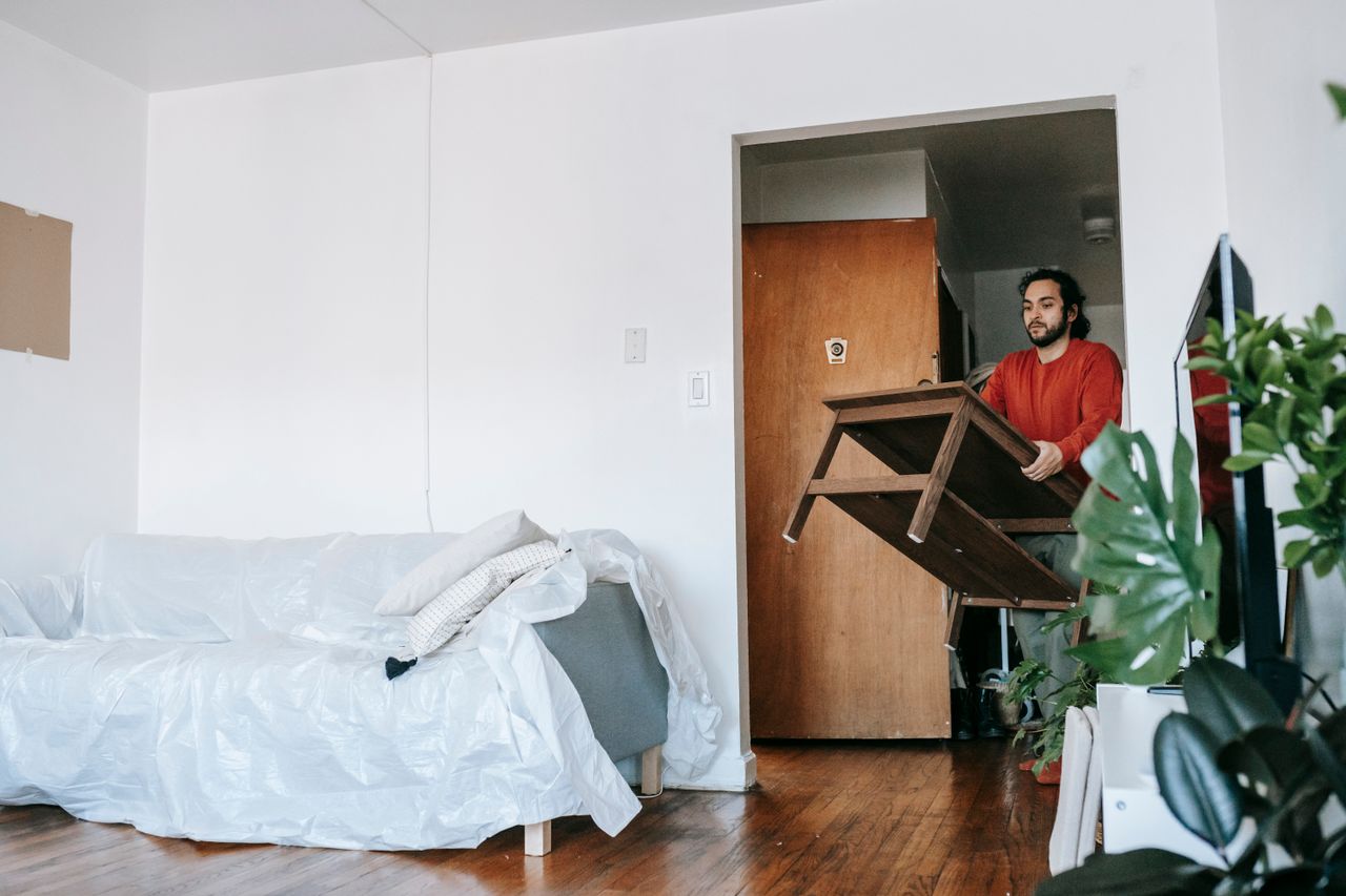 services-01 Man holding a wooden table during relocation in a contemporary apartment.
